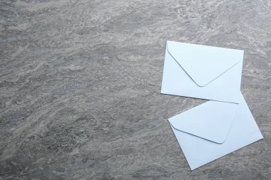 Gri arka planda beyaz kağıt zarflar, düz yatış. Metin için boşluk