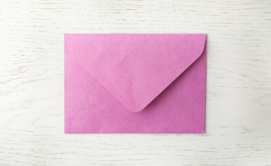 Beyaz ahşap zemin üzerinde pembe kağıt zarf, üst görünüm