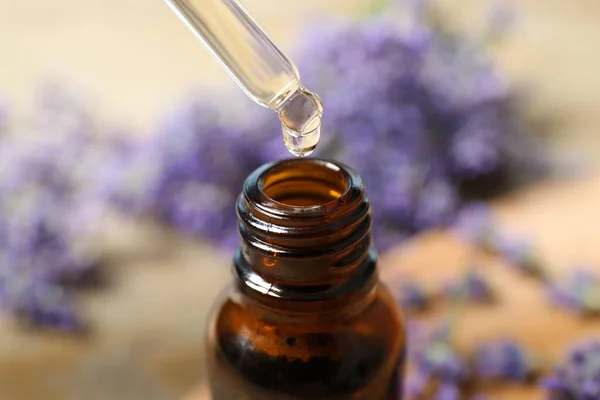 Dripping lavender essential oil into bottle, closeup