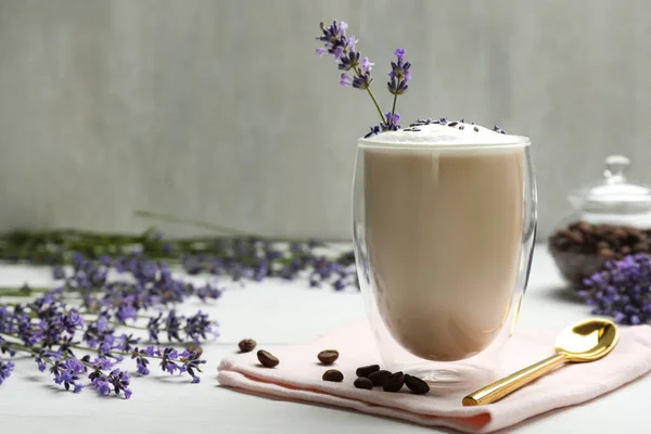 Delicious coffee with lavender and beans on white wooden table. Space for text