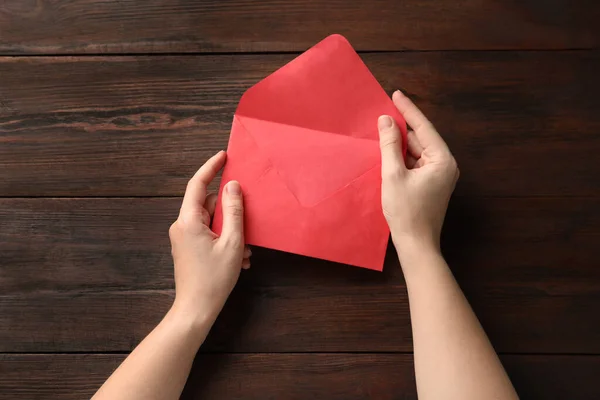 Vrouw Met Rode Papieren Envelop Aan Houten Tafel Bovenaanzicht — Stockfoto