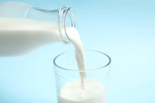 Milch Glas Gießen Auf Hellblauem Hintergrund Nahaufnahme — Stockfoto