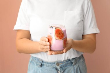 Pembe arka planda incirli smoothie tutan kadın, yakın plan.