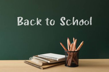 Yeşil karatahtanın yanındaki ahşap masa üzerinde 