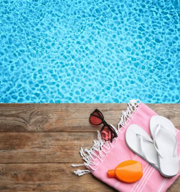 Plaj aksesuarları yüzme havuzunun yanındaki ahşap güvertede, düz yerde. Metin için boşluk 