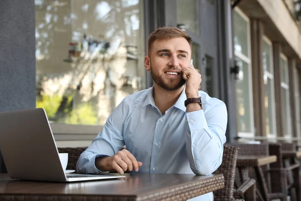 Bilgisayarlı Genç Adam Açık Kafede Telefonla Konuşuyor — Stok fotoğraf