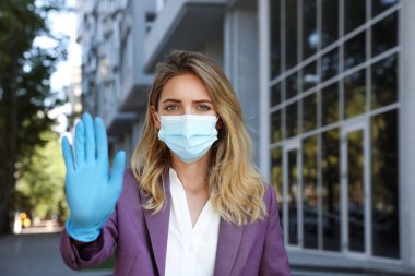 Koruyucu yüz maskeli kadın dışarıda durmayı gösteriyor. Koronavirüsün yayılmasını engelle