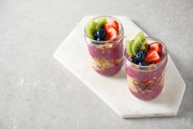 Acai smoothie, granola ve mermer masada böğürtlenli tatlı. Metin için boşluk