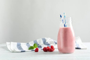 Yummy raspberry smoothie in glass bottle on table. Space for text  clipart