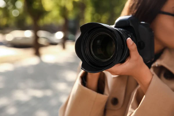 Private detective with camera spying outdoors, closeup