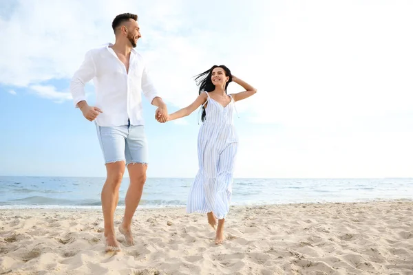 一对快乐的年轻夫妇一起在海滩上奔跑 — 图库照片