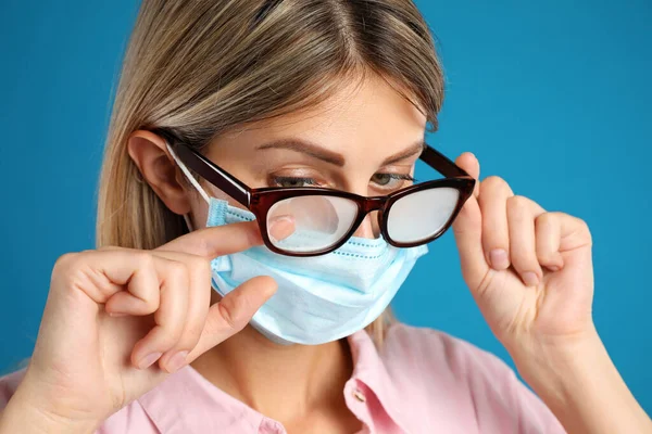 Kobieta Wycierająca Mgliste Okulary Spowodowane Przez Noszenie Jednorazowej Maski Niebieskim — Zdjęcie stockowe