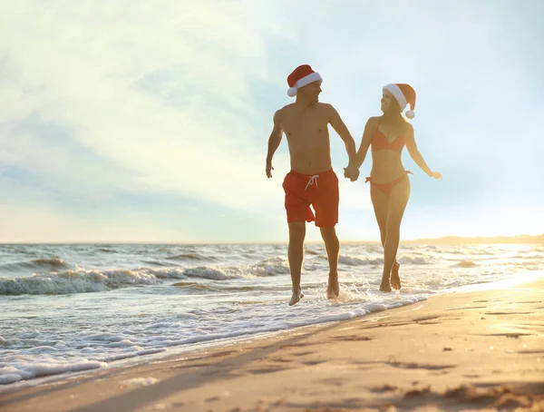 Glückliches Paar Mit Nikolausmützen Zusammen Strand Weihnachtsurlaub — Stockfoto