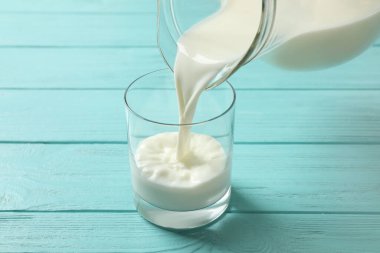 Sütü açık mavi ahşap masaya dökerek