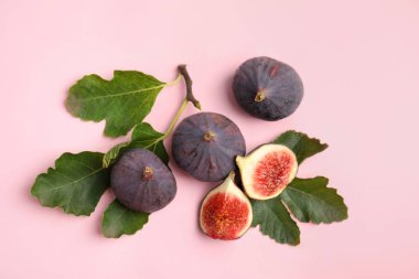Nefis olgun incirler ve pembe arka planda yeşil yapraklar.