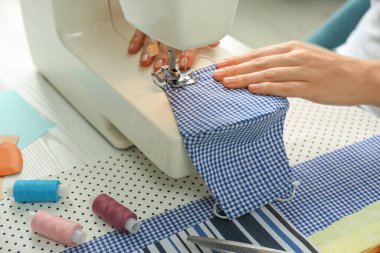 Masada makineli kumaş maskeli bir kadın, yakın plan. COVID-19 salgını sırasında kişisel koruma ekipmanları