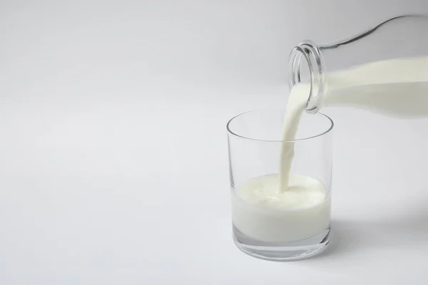牛乳を白い背景にガラスに入れる — ストック写真