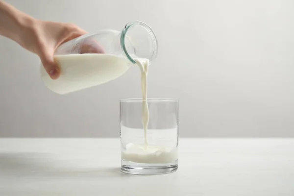 Vrouw Gieten Melk Glas Aan Witte Tafel Close — Stockfoto