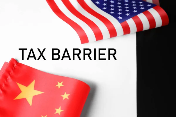 USA and China flags on paper with text TAX BARRIER, closeup