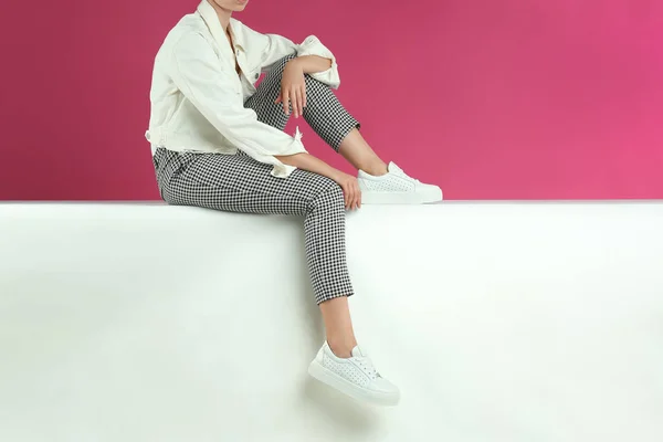 Frau Stilvollen Schuhen Sitzt Auf Farbigem Hintergrund Nahaufnahme — Stockfoto