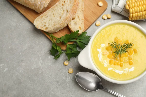 Delicious creamy corn soup served on grey table, flat lay