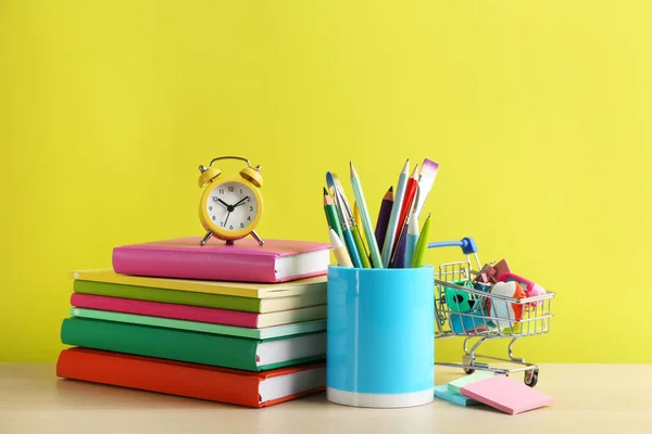Verschiedene Schulsachen Und Wecker Auf Dem Tisch Vor Gelbem Hintergrund — Stockfoto