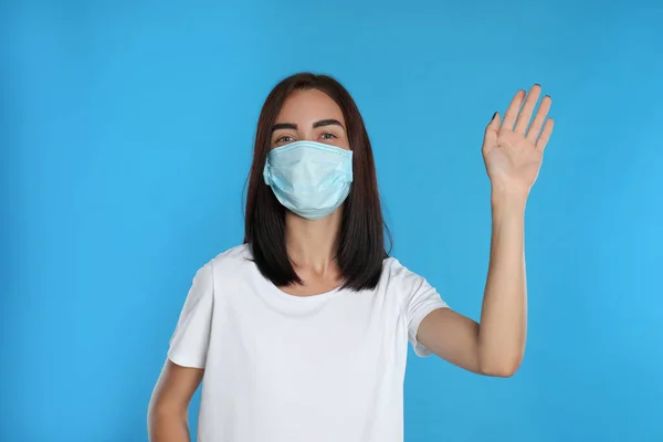 Young Woman Protective Mask Showing Hello Gesture Light Blue Background — Stock Photo, Image