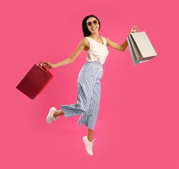 Schöne Junge Frau Mit Papiereinkaufstaschen Springt Auf Rosa Hintergrund — Stockfoto