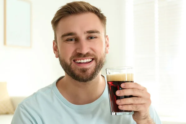 Handsome man with cold kvass indoors. Traditional Russian summer drink