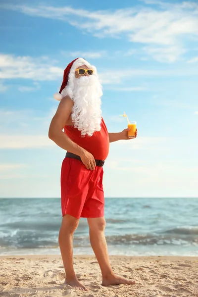 Santa Claus with cocktail on beach. Christmas vacation