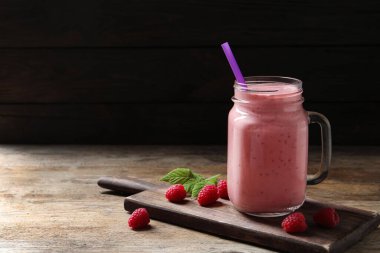Ahşap masadaki mason kavanozunda nefis ahududu smoothie. Metin için boşluk