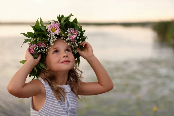 かわいい女の子は川の近くに美しい花で作られた花輪を着て — ストック写真