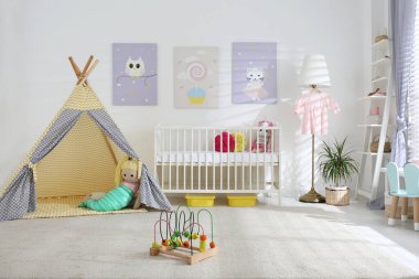 Bebek odasının içinde sevimli posterler, çadır ve rahat bir beşik var.