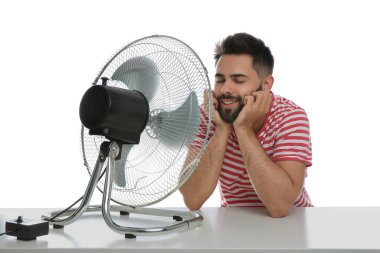 Adam beyaz arka planda vantilatörden hava akımının keyfini çıkarıyor. Yaz sıcağı