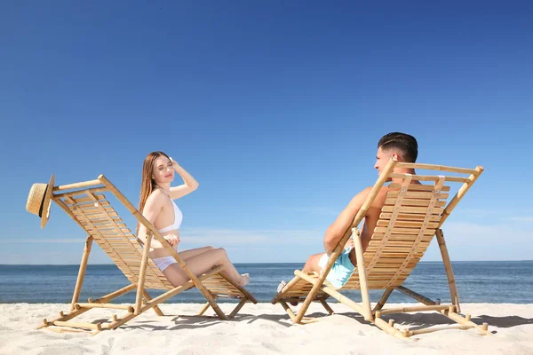 穿着比基尼的女人和她的男朋友坐在海滩的躺椅上 幸福的夫妻 — 图库照片