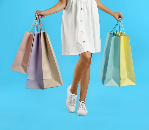 薄い青の背景に紙の買い物袋を持つ若い女性 クローズアップ — ストック写真