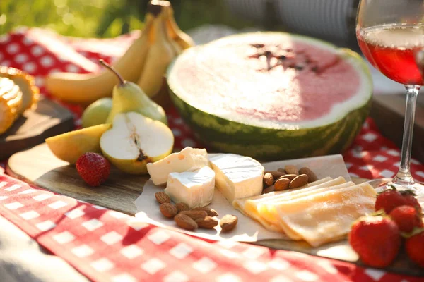 Picnic blanket with delicious food and drinks outdoors on sunny day, closeup