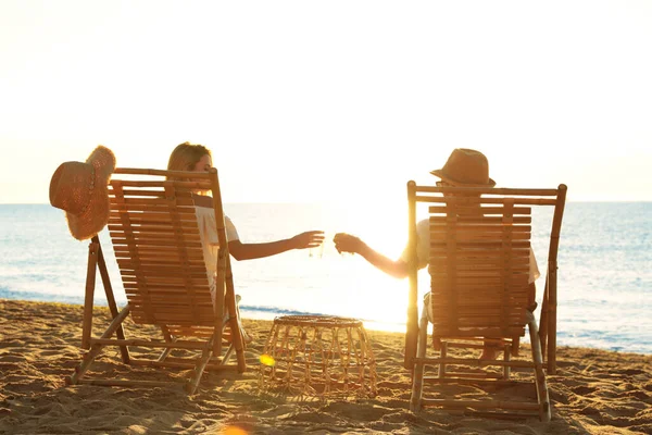 砂浜でデッキチェアでリラックスしているカップル 夏休み — ストック写真