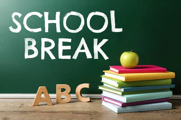 Text School Break on green chalkboard near table. Seasonal holidays
