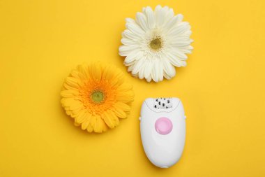 Modern epilator ve sarı arka planda çiçekler, düz yatıyordu. 