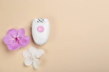 Bej arka planda modern epilator ve orkide çiçekleri, üst manzara. Metin için boşluk