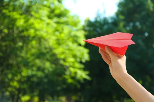 Woman holding paper plane outdoors, closeup. Space for text