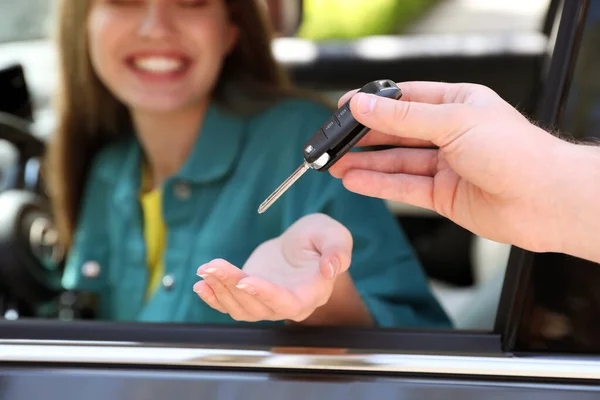 Salesperson giving car key to customer, focus on hands