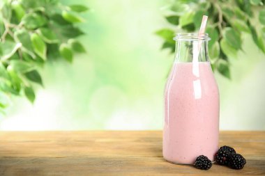 Lezzetli taze milkshake ve ahşap masada böğürtlen. Metin için boşluk