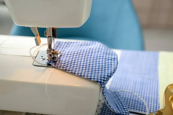 Sewing machine with cloth mask on table, closeup. Personal protective equipment during COVID-19 pandemic