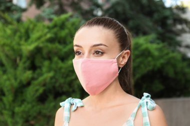 Dışarıda el yapımı kumaş maskeli bir kadın. COVID-19 salgını sırasında kişisel koruma ekipmanları