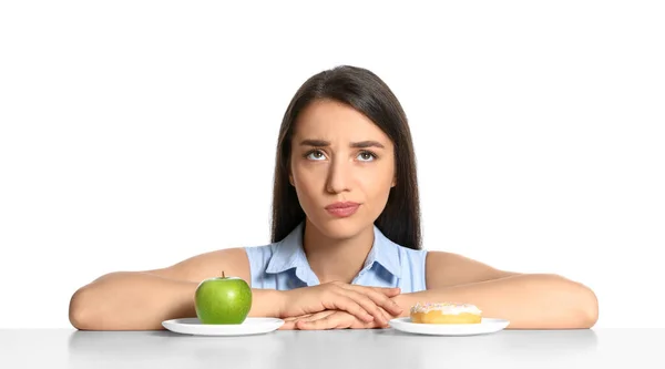 Αμφιβολία Γυναίκα Επιλέγοντας Μεταξύ Μήλου Και Ντόνατ Στο Τραπέζι Λευκό — Φωτογραφία Αρχείου