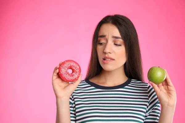 Mujer Eligiendo Entre Manzana Donut Sobre Fondo Rosa — Foto de Stock