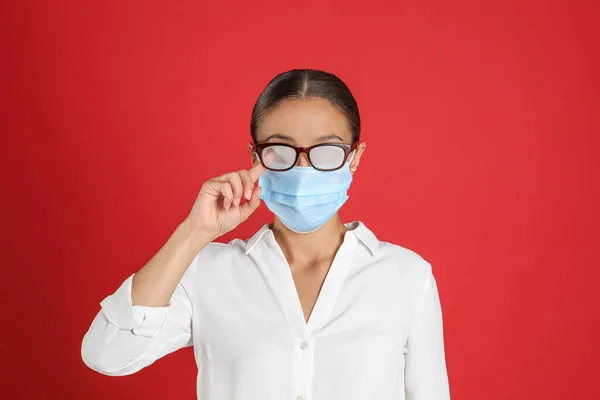 Kırmızı Arka Planda Tıbbi Maske Takan Bir Kadın Sisli Gözlük — Stok fotoğraf
