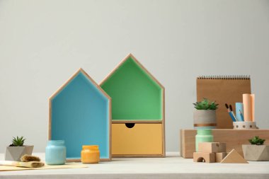 Ev şekilli raflar ve beyaz masa üzerinde boya kavanozları olan kompozisyon. İç elementler